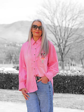 Frau trägt die OFF#DLY Bluse Anna pink mit Oversize-Schnitt und Brusttasche, kombiniert mit Jeans. Die Bluse fällt lässig, ideal für einen entspannten, modischen Alltagslook.