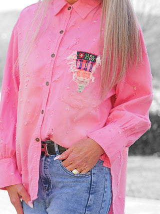 OFF#DLY Bluse Anna pink: Torso in pinker, langärmeliger Bluse mit Destroy-Look, bunter Patch auf Brusttasche, kombiniert mit mittelblauen Jeans.