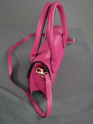 OFF#DLY Ledertasche pink aus 100 % Leder mit Tragehenkel und Riemen auf grauer Oberfläche, Größe 20x18x7 cm, modisches Accessoire mit Schnallen und Schulterriemen.