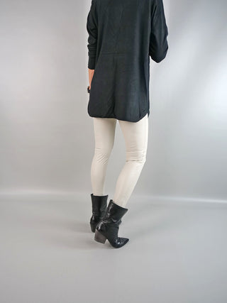 OFF#DLY Legging Creme, getragen von einer Person, kombiniert mit schwarzen Stiefeln. Die cremefarbene Legging betont einen schlichten, eleganten Look, passend für legere Anlässe. Material: 100% Polyester.