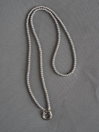 Kugelkette schmal Edelstahl Silber, eine silberne Halskette mit einem Anhänger, gefertigt aus Edelstahl. Die Kette ist 100 cm lang mit 3 mm Kugeldurchmesser und liegt auf einer grauen Oberfläche.