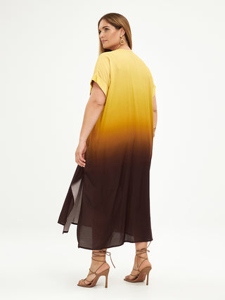 Frau trägt Mat Dress 8101.7078 in blassem Gelb aus 100% Viskose, mit langen Haaren und Ohrringen, zeigt Detailansicht der Schuhe und des Stoffes, wodurch das elegante Design hervorgehoben wird.