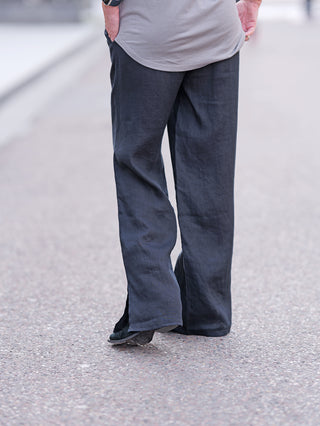 Gitta Banko Hose Alina: Leichte, lässige Leinenhose, leicht oversized, getragen von einer Person im Freien. Sichtbar sind Beine in blauer Hose und Füße auf dem Gehweg.