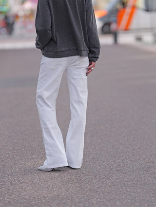 Person trägt OFF#DLY Wide Leg Denim Romina, weiße weite Hose, kombiniert mit grauem Pullover. Modell zeigt Rückansicht, betont lässigen Schnitt und modischen Street-Style.