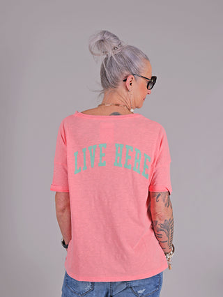 Frau mit Tattoos trägt das One Tee Margareth coral, ein kurzärmeliges T-Shirt mit Frontprint, aus 100% Baumwolle.