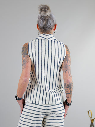 SOHO-t Gilet Gilda beige blue, getragen von einer tätowierten Person. Detailansicht der Knopfschlaufen vorne. Baumwoll-Polyester-Mischung verleiht dem Gilet eine strukturierte Optik.