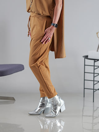 Eine Person trägt die SOHO-t Pant Inagi zimt, kombiniert mit silbernen Stiefeln. Die Hose sitzt eng und betont die Beine. Das Model ist 172 cm groß und trägt Größe M.
