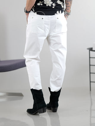 Eine Person trägt die Thom Krom Pant off white, eine lässige Joggpant mit Taschen, kombiniert mit schwarzen Stiefeln. Die Hose hat einen Gummibund und Kordel, fällt größer aus.